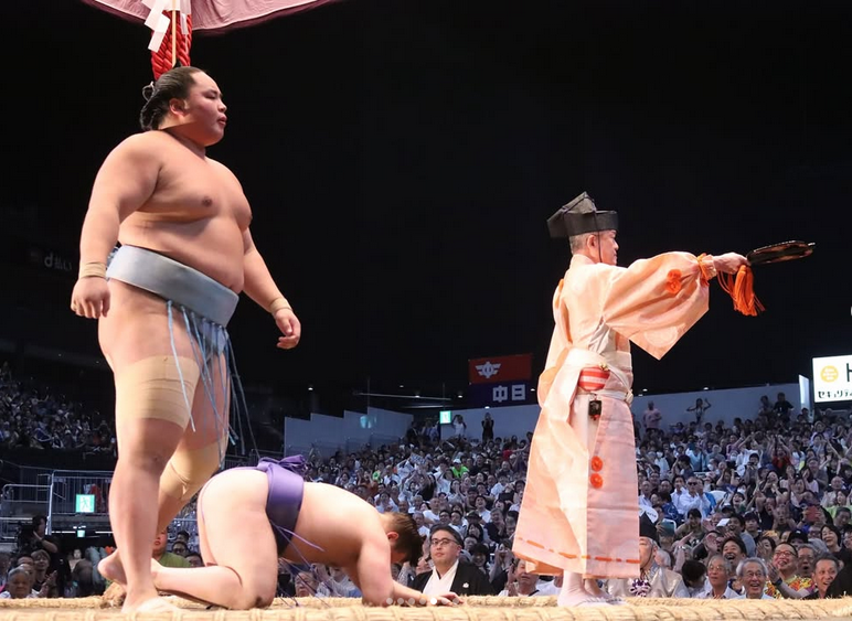 Sumo wrestler Kotoshoho stands over Aonishiki after he won the 2025 Nagoya basho.